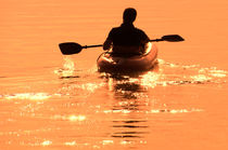 Man paddling with boat in the sunset by Christian Zirsky