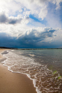 Cloudy sky over a wavy beach by Jessy Libik