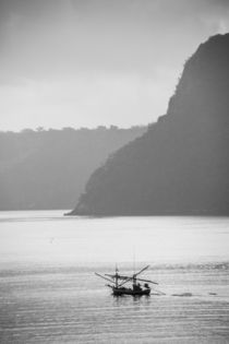 thai fisherboat in front of steep island by anando arnold