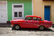 Red old car in front of colourful houses, Cuba by Bastian Linder
