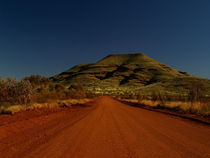 Australia dirt road with red sand in front of green hill von Bastian Linder