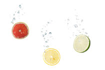 Grapefruit, lemon, lime in water with air bubbles by Bastian Linder