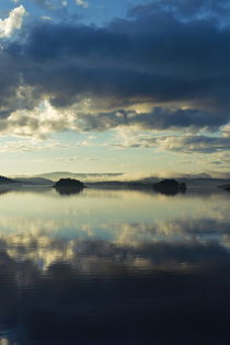 Two islands and the cloudy sky are reflected in a glassy lake by Intensivelight Panorama-Edition