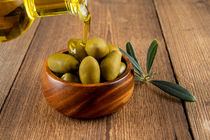 Olivenöl und grüne Oliven in Holzschale - Olive oil and green olives in wooden bowl von Thomas Klee