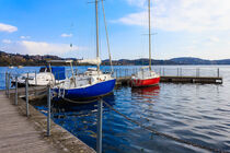 a lacustre landscape with colored boats anchored to the pier by susanna mattioda