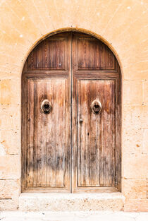 Old mediterranean house with vintage wooden front door and stone arch von Alex Winter