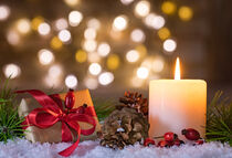 Christmas present and candle with natural decoration on snow by Alex Winter