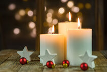 Three white christmas candles with white and red ornaments by Alex Winter