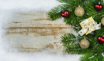 Klassische Weihnachtsdeko mit Tannenzweigen, Weihnachtsschmuck und Schnee-Rahmen auf Holz von Alex Winter