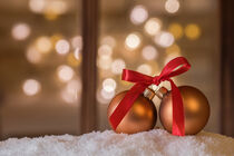 Golden christmas balls with red ribbon on snow by Alex Winter