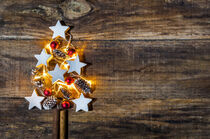 Xmas tree decoration with lights, red christmas balls, white stars and pine cones on wood by Alex Winter