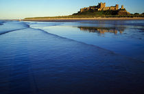 Gentle waves on Northumbrian coast, distant Bamburgh Castle, Bamburgh, England. von Panoramic Images