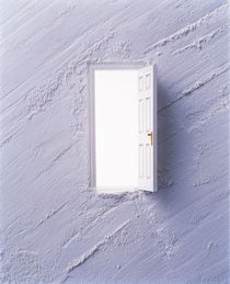 Open white door floating in center of light grey plaster wall von Panoramic Images