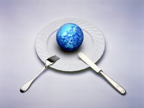 Small globe sitting on white plate with knife and fork by Panoramic Images