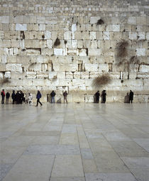 Group of people praying in front of a wall by Panoramic Images