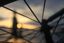 Person through bike spokes at beach sunset by Charles Harker