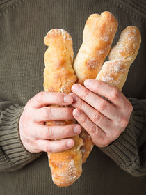 Mann hält französische Baguettes von Elisabeth Cölfen