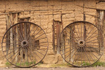 Old wagon wheels in front of mud-brick barn von Danita Delimont