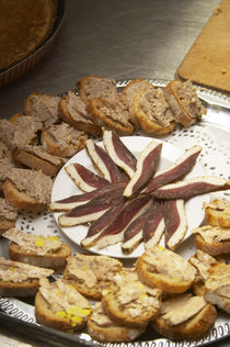 Duck appetizers: dried duck breast and small canapes pieces of bread with duck rillette Ferme de Biorne duck and fowl farm Dordogne France by Danita Delimont