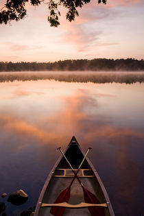A canoe rests on the shore of Pawtuckaway Lake at dawn as seen from Horse Island in New Hampshire's Pawtuckaway State Park by Danita Delimont