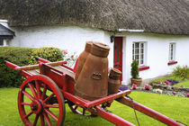 Metal containers on cart and thatched roof cottage von Danita Delimont