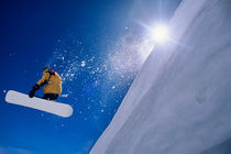 Man flying through the air on a snowboard with the sun over his shoulder in the Wasatch Mountains of northern Utah by Danita Delimont