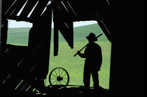 Silhoette of farmer in barn by Danita Delimont