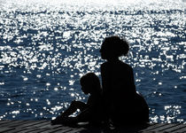 Profiles of mother and daughter against the glittering sea von Waldek Dabrowski