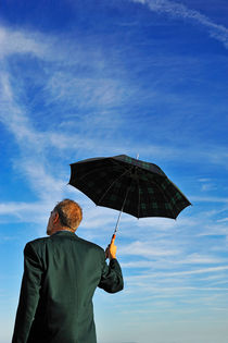 Businessman looking at sky holding umbrella by Sami Sarkis Photography