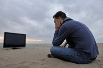 Man with TV on beach at sunset by Sami Sarkis Photography