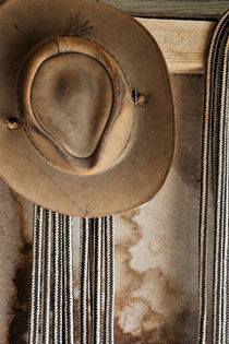 Old leather hat and ropes hanging at stable by Sami Sarkis Photography