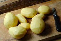 Peeled raw potatoes on cutting board by Sami Sarkis Photography