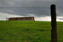 Barbed wires and haystack shelter in field by Sami Sarkis Photography