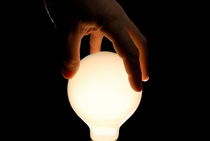 Man's hand on illuminated light bulb von Sami Sarkis Photography