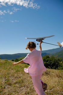 Girl (6-7) flying model plane in field by Sami Sarkis Photography