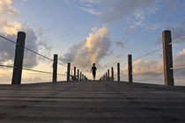 Woman running on wooden jetty at sunrise by Sami Sarkis Photography