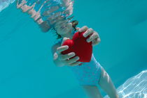 Girl (6-7) holding heart shaped symbol in swimming pool von Sami Sarkis Photography