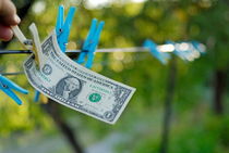 Man's hand taking one US dollars banknote hanging on clothesline by Sami Sarkis Photography