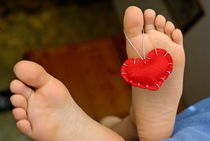 Valentine heart hanging on girl's (6-7) barefeet by Sami Sarkis Photography