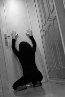 Woman kneeling in corridor with hands on closed door von Sami Sarkis Photography