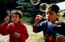 Girl and boy blowing bubble-wands by Sami Sarkis Photography