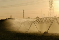 Sprinklers spraying water in field by Sami Sarkis Photography