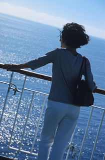 Woman looking out to sea from deck of boat by Sami Sarkis Photography
