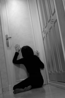 Woman sitting in corridor with hands on closed door von Sami Sarkis Photography