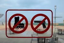 Restaurant entrance door with 'firearms' and 'roller-skates' forbidden sign by Sami Sarkis Photography