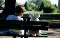 Boy (7-9) sitting on park bench with teddy bear by Sami Sarkis Photography