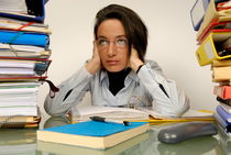 Mature office worker sitting at desk with piles of folders by Sami Sarkis Photography