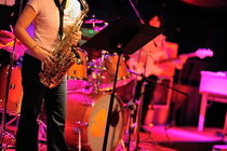 Woman playing saxophone on stage with her band by Sami Sarkis Photography