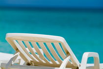 Empty white deck chair on a beach with bright blue waters von Sami Sarkis Photography