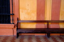 Long wooden bench against a yellow wall at the Alcazar of Seville von Sami Sarkis Photography